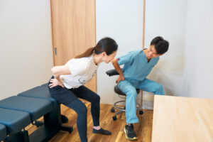 腰の動きを確認しながら自宅でのケアやストレッチ指導を行う様子　名古屋市中区鶴舞のかんとま整骨院