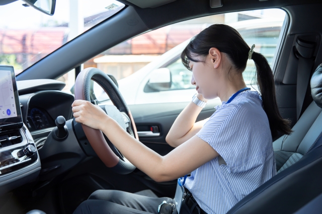 車の運転中に首の痛みを感じる女性　交通事故のむちうちや肩こりに悩む人のイメージ