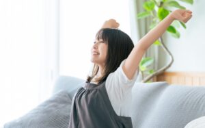 朝の伸びでスッキリとした表情の女性　自律神経が整い心も身体も軽くなる名古屋市中区鶴舞のかんとま整骨院